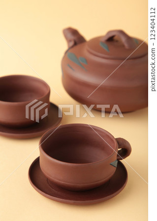 Clay teapot with cups on beige background Clay teapot with cups on beige background 123404112