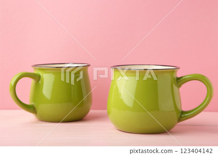 Green mugs on pink background with copy space 123404142