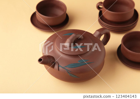 Clay teapot with cups on beige background Clay teapot with cups on beige background 123404143