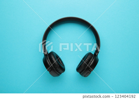 Black, modern wireless headphones on a blue background. 123404192