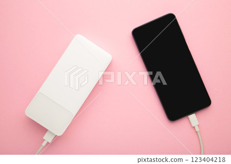 White powerbank charges smartphone on pink background. White powerbank charges smartphone on pink background. 123404218