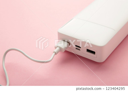 Portable powerbank with usb cable on pink background. 123404295