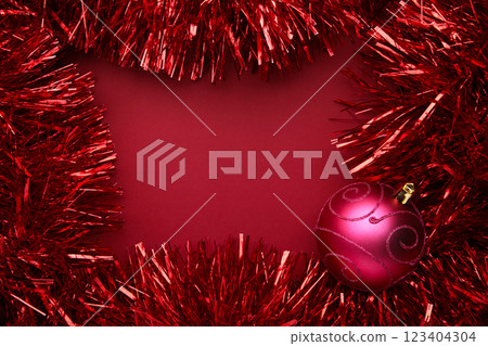 Tinsel with ball on red background. Space for text Tinsel with ball on red background. Space for text 123404304
