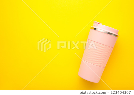 Pink thermo cup or thermos mug for tea or coffee on yellow background. Hot beverage Pink thermo cup or thermos mug for tea or coffee on yellow background. Hot beverage 123404307