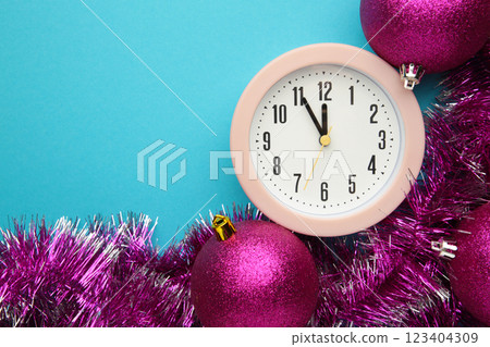 New Year's clock decorated with christmas tinsel and ball. Celebration Concept for New Year Eve. New Year's clock decorated with christmas tinsel and ball. Celebration Concept for New Year Eve. 123404309