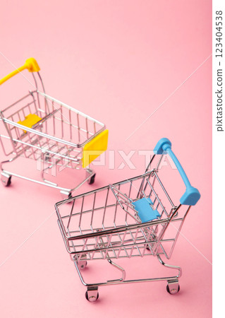 Mini shopping trolleys on pink background. Vertical photo 123404538