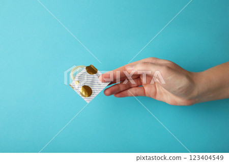 Hand holding a condom on blue background 123404549