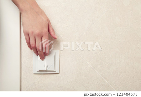 Female hand pressing light switch in apartment closeup Female hand pressing light switch in apartment closeup 123404573