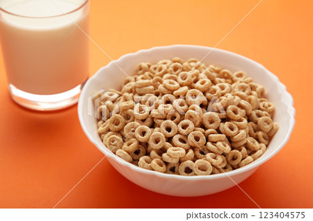 Bowl with cereals and a glass bottle of milk on orange background. Bowl with cereals and a glass bottle of milk on orange background. 123404575