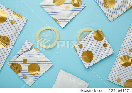 Opened condom and condom in pack on blue background. A condom use to reduce the probability of pregnancy or sexually transmitted disease Opened condom and condom in pack on blue background. A condom use to reduce the probability of pregnancy or sexually transmitted disease 123404597