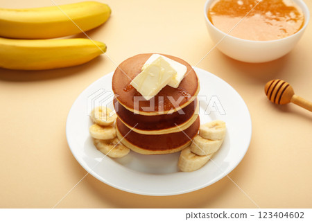 Plate with yummy banana pancakes on beige background. 123404602