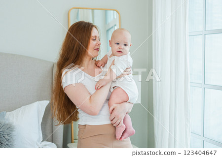 Happy family at home. Mother holding little toddler child daughter. Mom and baby girl relax playing having fun together at home. Mother hugs baby with love care. Mom of breast feeding baby Happy family at home. Mother holding little toddler child daughter. Mom and baby girl relax playing having fun together at home. Mother hugs baby with love care. Mom of breast feeding baby 123404647