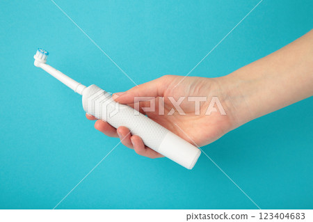Woman holding electric toothbrush on blue background 123404683
