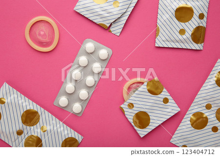 Contraceptive pills and condoms on pink background. Concept of birth control Contraceptive pills and condoms on pink background. Concept of birth control 123404712