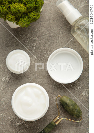 Face massage roller with cosmetic cream on grey background. Vertical photo 123404743