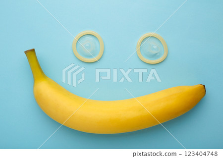 Condom and banana on blue background with copy space 123404748