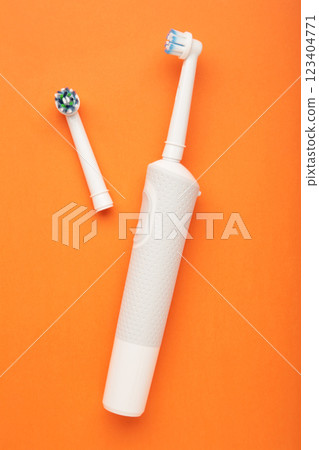 Modern electric toothbrush on orange background. Controlled tool for daily oral care. Modern electric toothbrush on orange background. Controlled tool for daily oral care. 123404771