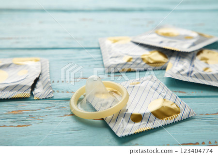 Opened condom and condom in pack on blue background. A condom use to reduce the probability of pregnancy or sexually transmitted disease Opened condom and condom in pack on blue background. A condom use to reduce the probability of pregnancy or sexually transmitted disease 123404774