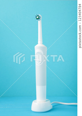 Modern electric toothbrush with charger on blue background 123404784