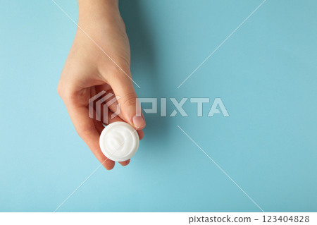 Close up woman hands holding bottle of white face cream on grey background. Skin care Close up woman hands holding bottle of white face cream on grey background. Skin care 123404828