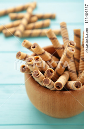 Coffee wafer stick roll with coffee cream in bowl on blue background. Coffee wafer stick roll with coffee cream in bowl on blue background. 123404887