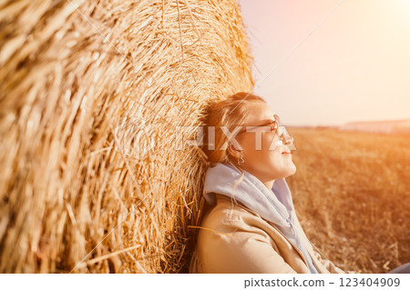 Smiling Woman Resting Against Hay Bale Smiling Woman Resting Against Hay Bale 123404909