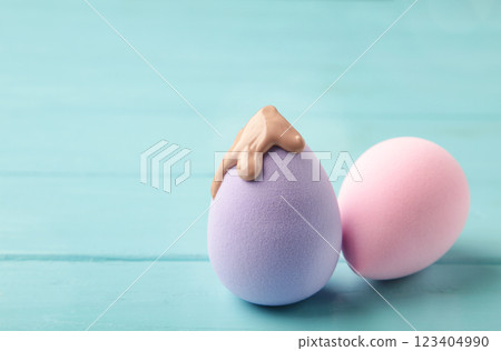Liquid beige makeup foundation on new purple sponges on blue background 123404990