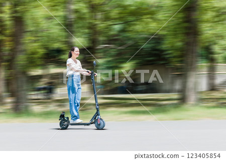 一位年輕女子在電動滑板上清爽地奔跑 一位年輕女子在電動滑板上清爽地奔跑 123405854