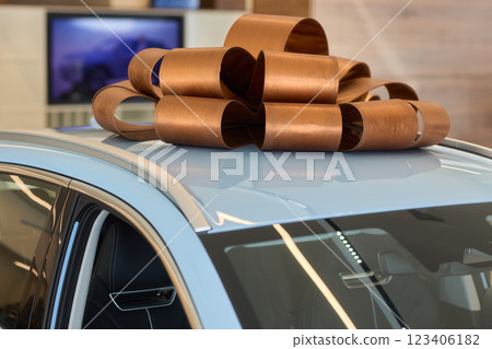 An iconic new car is being presented with a ribbon bow at the showroom for a celebratory event An iconic new car is being presented with a ribbon bow at the showroom for a celebratory event 123406182