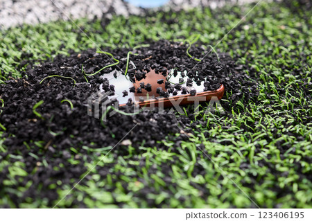 Artistic Layout Showcasing a Beautiful Brown Boat Resting on Black Pebbles and Lush Green Grass 123406195