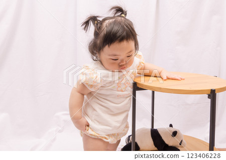 [Baby with twin tails standing up holding onto a table] 123406228