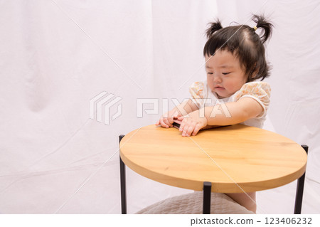 [Pigtailed baby standing on a table with smartphone] 123406232