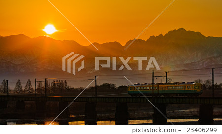The Toyama Chiho Railway crosses the Jōganji River with the rising sun over the Tateyama mountain range in the background. The Toyama Chiho Railway crosses the Jōganji River with the rising sun over the Tateyama mountain range in the background. 123406299