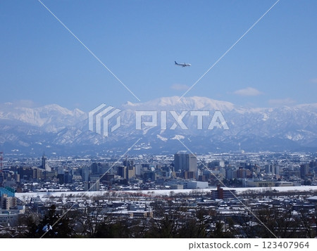 A passenger plane preparing to land and the snow-capped city of Toyama with Mount Yakushi in the background A passenger plane preparing to land and the snow-capped city of Toyama with Mount Yakushi in the background 123407964