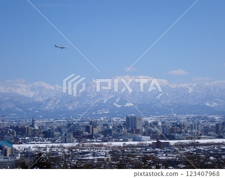 A passenger plane preparing to land and the snow-capped city of Toyama with Mount Yakushi in the background A passenger plane preparing to land and the snow-capped city of Toyama with Mount Yakushi in the background 123407968