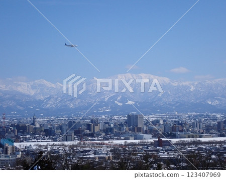 A passenger plane preparing to land and the snow-capped city of Toyama with Mount Yakushi in the background A passenger plane preparing to land and the snow-capped city of Toyama with Mount Yakushi in the background 123407969