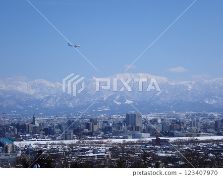 一架準備降落的客機，背景是白雪皚皚的富山市和藥師山 123407970