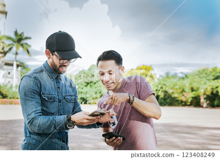 Two young friends having fun with the cell phone outdoors. Two happy friends looking at a cell phone in the street, Two smiling friends looking at media on the cell phone in the street 123408249