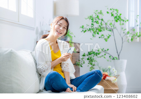 Woman sitting on a sofa and looking at a smartphone 123408602