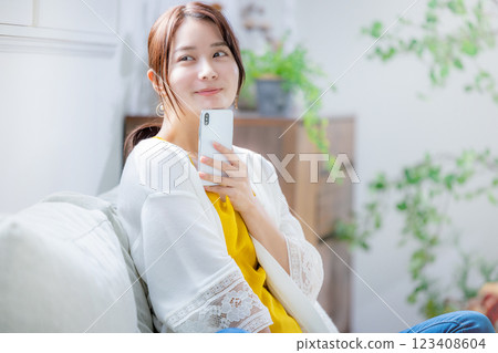 Woman sitting on a sofa and looking at a smartphone 123408604