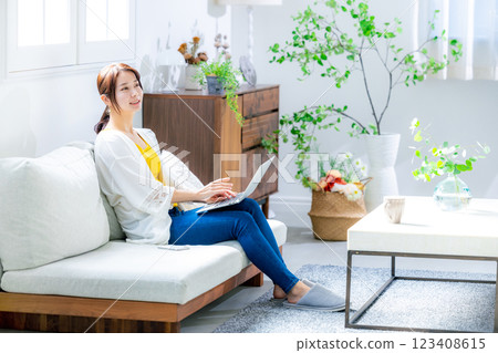 使用一台電腦在客廳裡的年輕女子 123408615