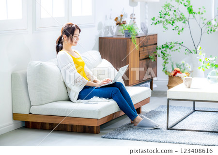 使用一台電腦在客廳裡的年輕女子 123408616