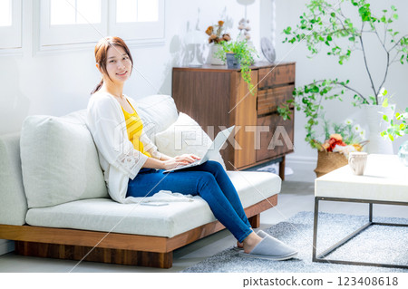 使用一台電腦在客廳裡的年輕女子 123408618