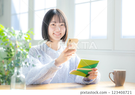 A woman looking at her bankbook and smartphone A woman looking at her bankbook and smartphone 123408721