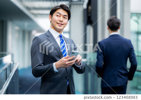A businessman operating a smartphone at the office A businessman operating a smartphone at the office 123408983