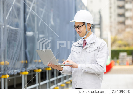 穿著工作服的男人拿著筆記型電腦 123409008