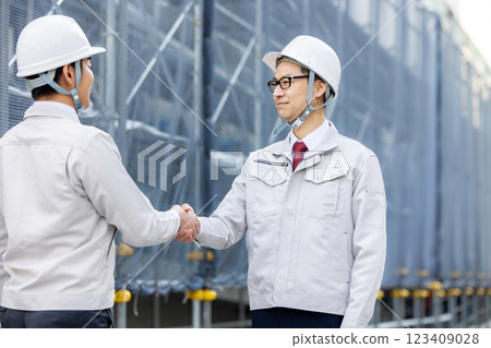 Workers working at a construction site shaking hands 123409028