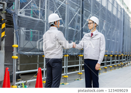 Workers working at a construction site shaking hands 123409029