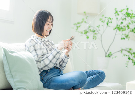 年輕女子用智慧型手機在沙發上放鬆 123409148