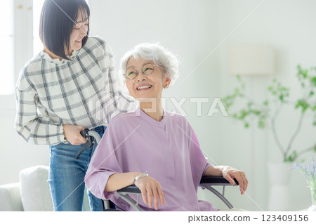 坐在輪椅上的祖母和她的孫女在客廳共度時光 坐在輪椅上的祖母和她的孫女在客廳共度時光 123409156